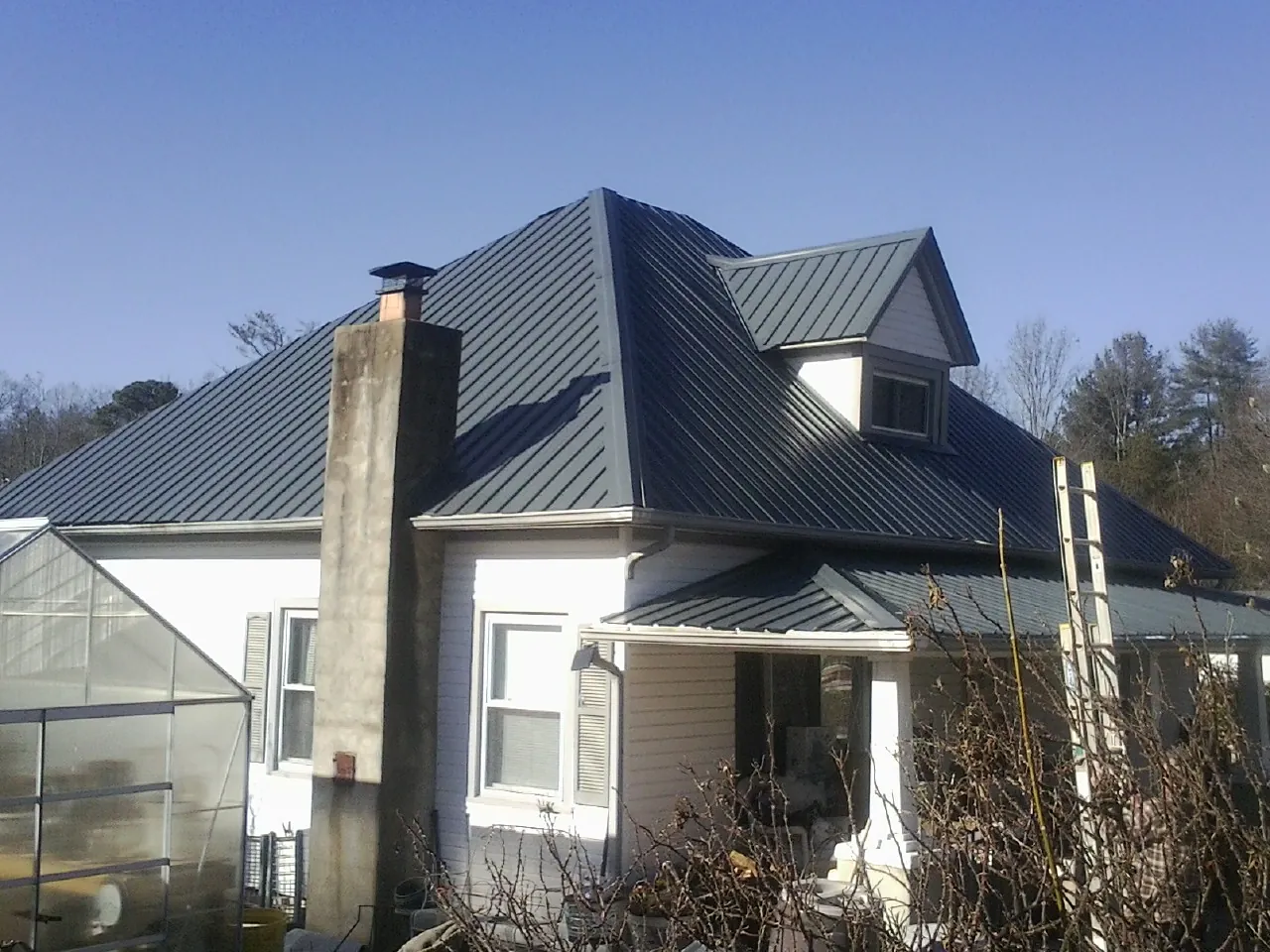 Dark blue standing seam metal roof on a white farmhouse with dormer — Slate & Tile Roof Repair by Roofing Brothers in Starlight
