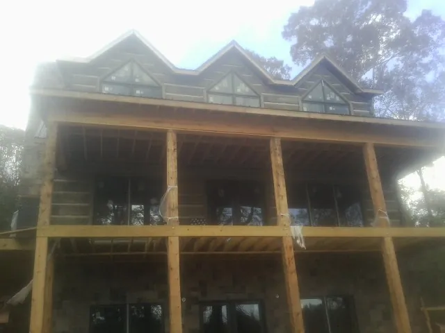Dormers and porch framing on a large log home under construction — Roof Coating work by our crew in Starlight