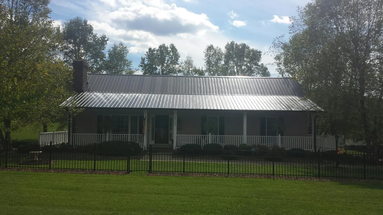 Gray metal roof on a brick ranch with a full width front porch — Gutter Guard Installation work by our crew in Starlight