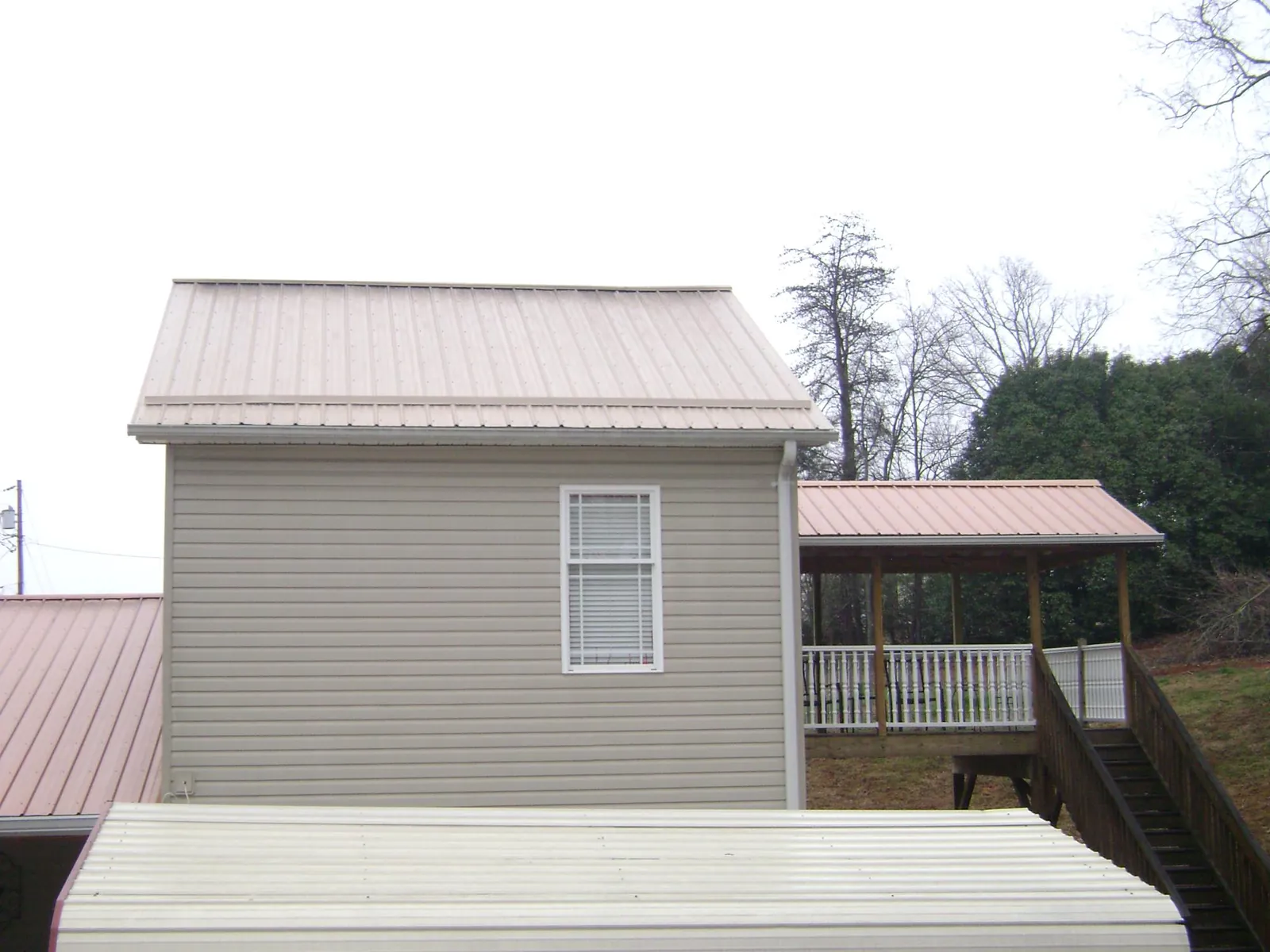 Tan metal roofs on a two story addition and attached porch, from a Roof Replacement job in Starlight