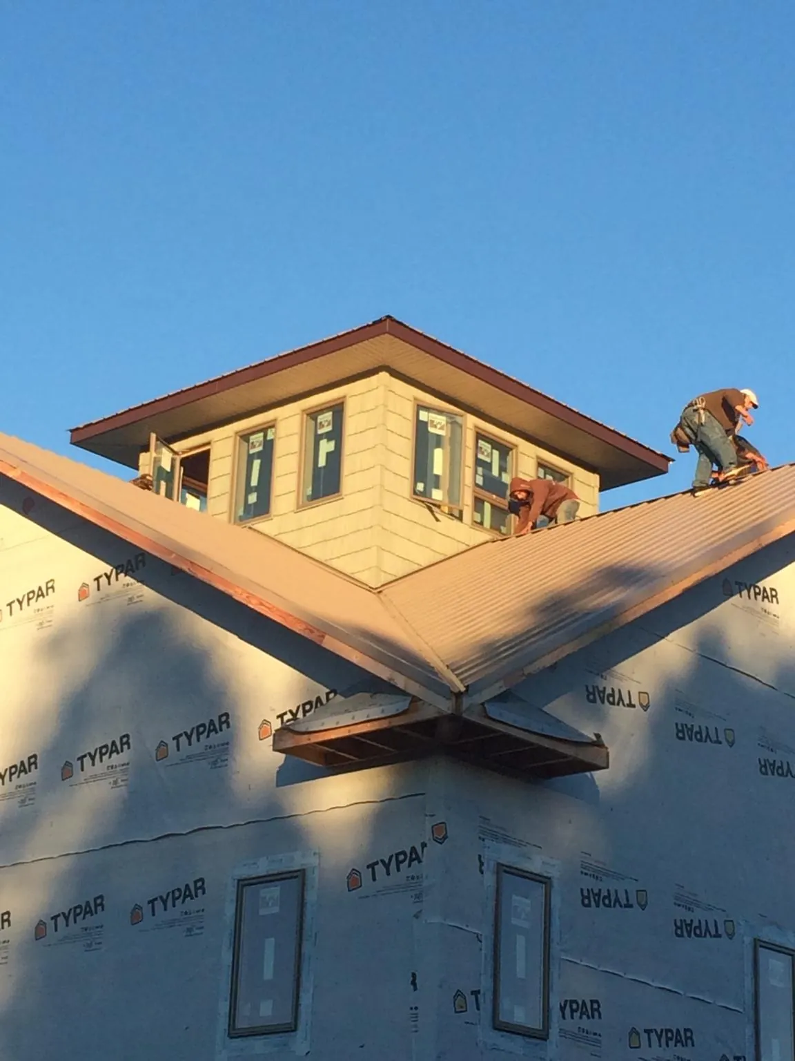 Roofers working around a rooftop cupola on a new metal roof at sunset — Roof Waterproofing in Starlight by Roofing Brothers